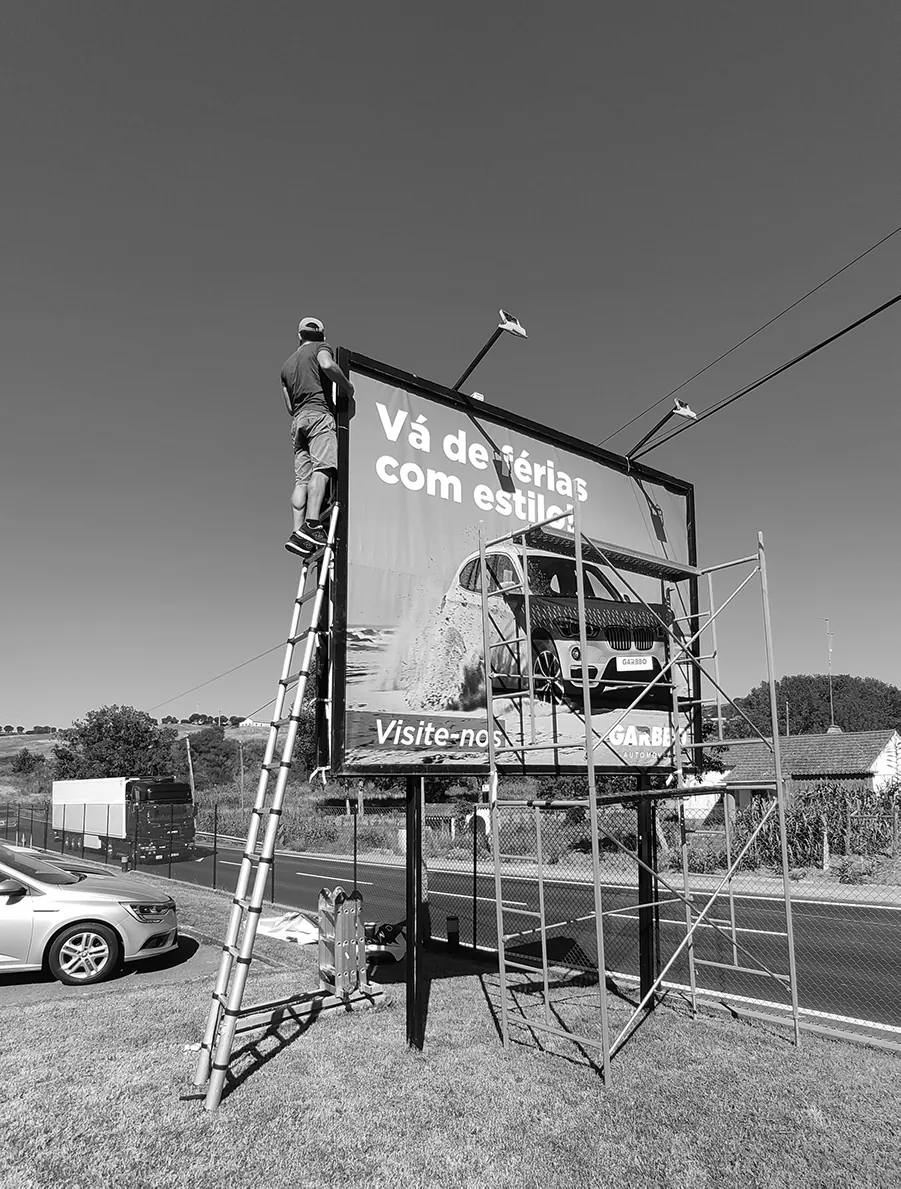 Técnico a montar a impressão de um outdoor à beira da estrada